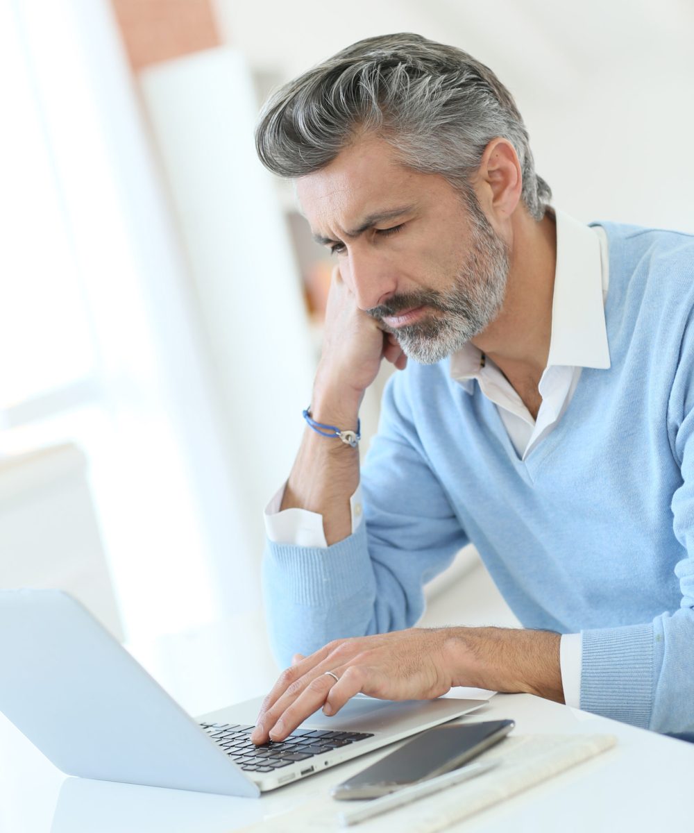 Trendy mature man working from home with laptop